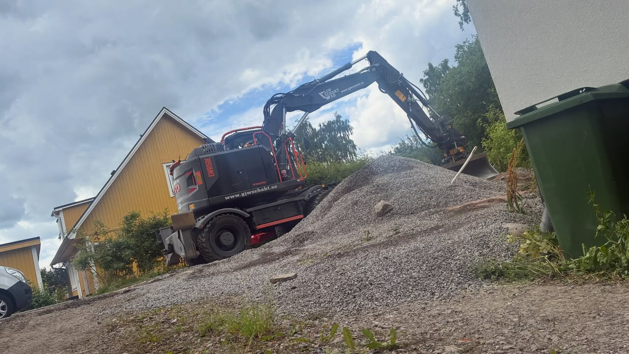 Gravmaskin vid grushög vid utlastning av grus på tomt i Kungsör